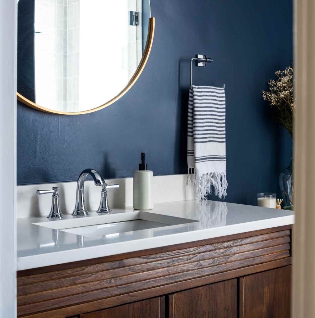 full-service-interior-designer-60613-unexpected-surprises-during-home-projects-bathroom-vanity-with-deep-blue-walls-round-mirror-personal-home-renovation