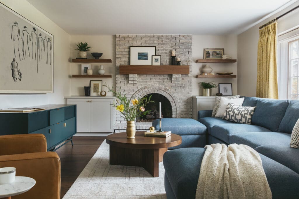 full-service-interior-designer-60613-should-you-remodel-or-move-renovated-living-room-arched-fireplace-large-custom-sectional-blue-tones-personal-home-furnishings