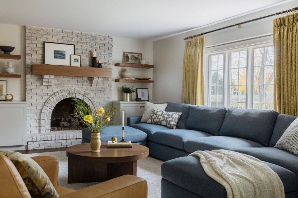 full-service-interior-design-60613-timeless-family-home-renovation-comfortable-family-room-large-blue-sectional-painted-brick-fireplace-wood-shelves-collected