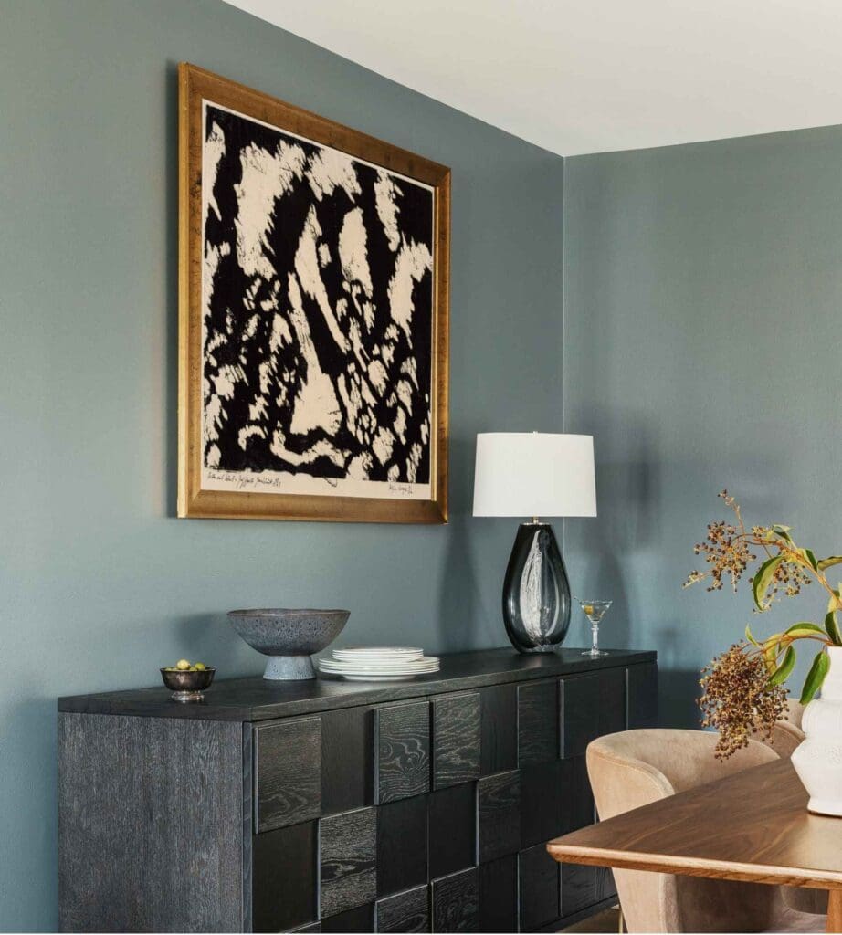 full-service-interior-design-chicago-il-curating-a-meaningful-art-collection-abstract-painting-hung-over-sideboard-in-dining-room-deep-teal-walls-sophisticated-remodel